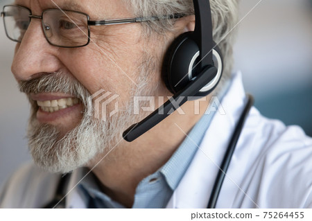 Close up of smiling mature male doctor in headphones Close up of smiling mature male doctor in headphones 75264455
