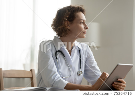 Pensive female doctor use tablet thinking of problem solution 75264716
