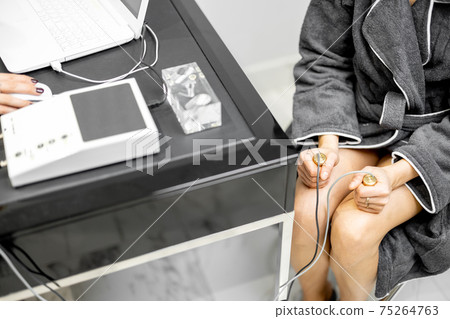 Woman takes hold of the brass handpieces of bioenergetic testing device 75264763