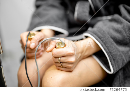 Woman takes hold of the brass handpieces of bioenergetic testing device 75264773
