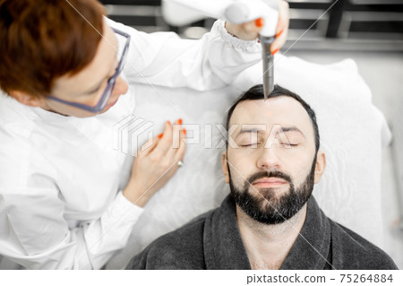 Cosmetologist doing laser facelifting procedure in beauty clinic 75264884