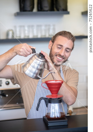 Smiling man pouring water into a pourover 75265622