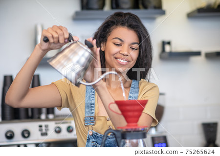 Pretty woman holding teapot over pouver 75265624