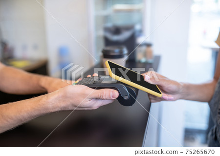 Male hands with terminal and female with smartphone 75265670