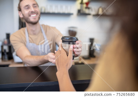 Man giving glass of coffee to womans hand 75265680