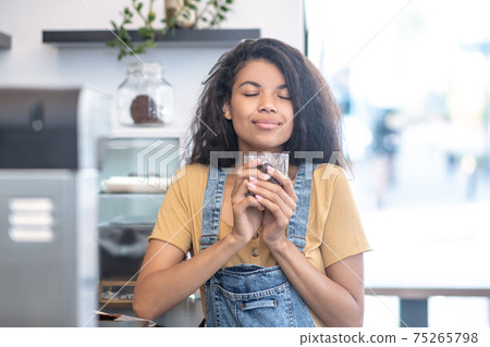Woman with closed eyes with glass of coffee beans Woman with closed eyes with glass of coffee beans 75265798