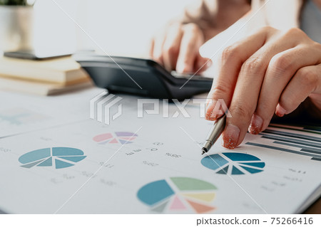 Close up of Business woman or accountant using calculator during analysis  75266416