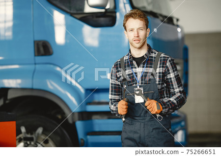 urly guy in coveralls and orange gloves standing next to a blue truck urly guy in coveralls and orange gloves standing next to a blue truck 75266651