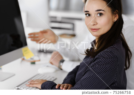 Business woman and man discussing questions while using computer at workplace in modern office. Teamwork, meeting and brainstorming concept 75266758