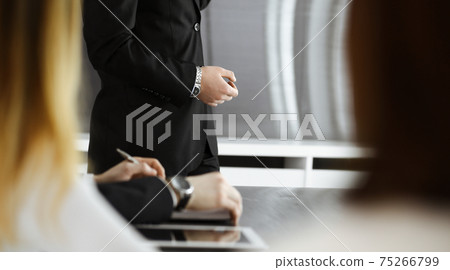 Business presentation. Unknown businessman giving a speech to colleagues or partners at corporate conference. Meeting concept Business presentation. Unknown businessman giving a speech to colleagues or partners at corporate conference. Meeting concept 75266799