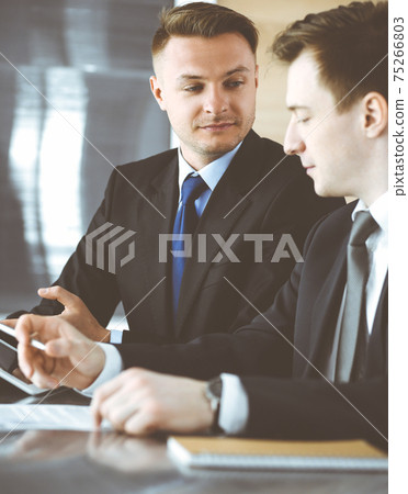 Businessman using tablet computer and work together with his colleague or partner at the glass desk in modern office. Unknown business people at meeting. Teamwork and partnership concept Businessman using tablet computer and work together with his colleague or partner at the glass desk in modern office. Unknown business people at meeting. Teamwork and partnership concept 75266803