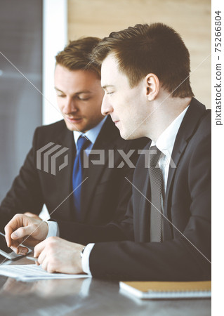 Businessman using tablet computer and work together with his colleague or partner at the glass desk in modern office. Unknown business people at meeting. Teamwork and partnership concept Businessman using tablet computer and work together with his colleague or partner at the glass desk in modern office. Unknown business people at meeting. Teamwork and partnership concept 75266804