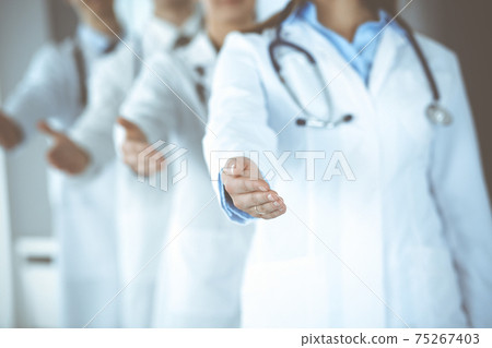 Group of modern doctors standing as a team whole offering helping hand for shaking hand or saving life. Medical help, insurance in health care, best desease treatment and medicine concept 75267403