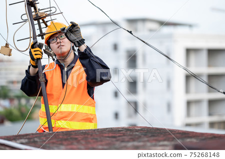 Asian worker repairing an old TV antenna on rooftop Asian worker repairing an old TV antenna on rooftop 75268148