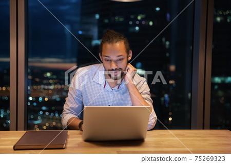 Close up thoughtful African American businessman using laptop at night 75269323