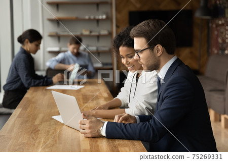 Close up smiling diverse colleagues working on online project together Close up smiling diverse colleagues working on online project together 75269331