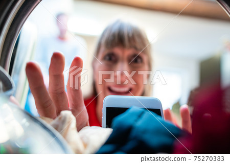 Woman finds her phone in washing drum Woman finds her phone in washing drum 75270383