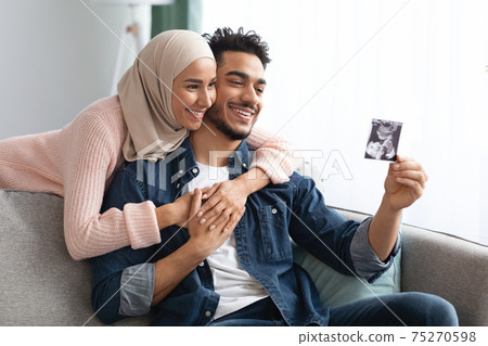 Pregnant Muslim Woman And Husband Looking At Baby Sonogram Picture At Home Pregnant Muslim Woman And Husband Looking At Baby Sonogram Picture At Home 75270598