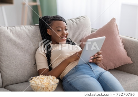 Carefree african american young lady using digital tablet Carefree african american young lady using digital tablet 75270786