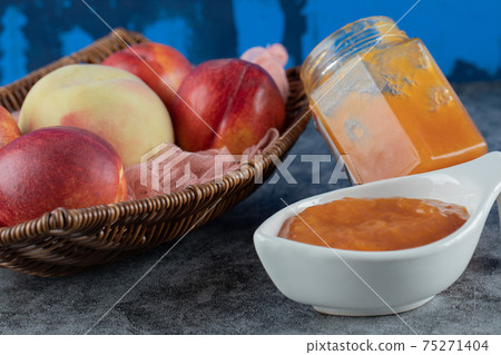 Peach and apples in a wooden basket on a piece of pink towel Peach and apples in a wooden basket on a piece of pink towel 75271404