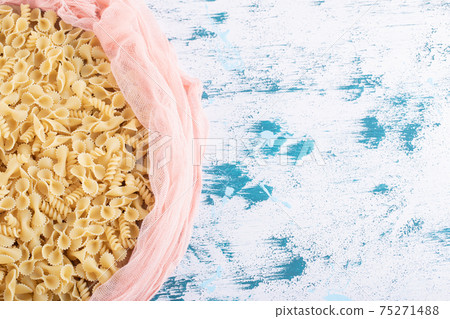 Dry macaroni inside pink cloth on colorful background Dry macaroni inside pink cloth on colorful background 75271488