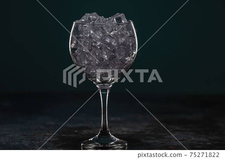 Glass full of ice standing on a table in the dark 75271822