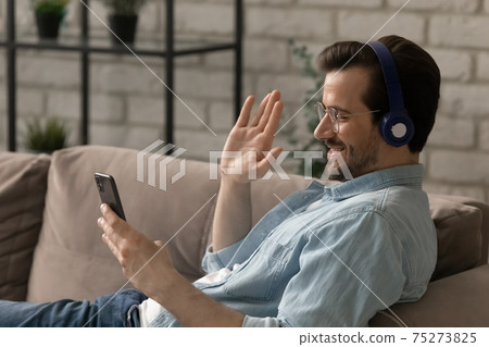 Smiling guy greet friend wave hand hello calling on phone 75273825