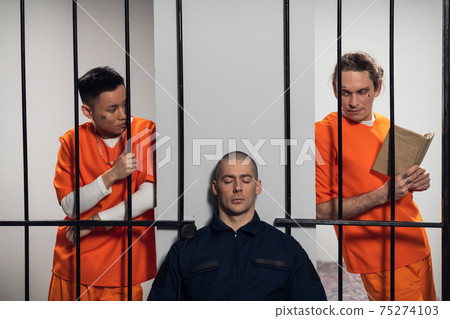 White and asian dangerous criminals and serial killers attack the armed guard who guards their cells. Stretching out his hands to the security guard through the bars. 75274103