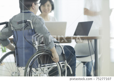 A man in a wheelchair working in the office A man in a wheelchair working in the office 75277107