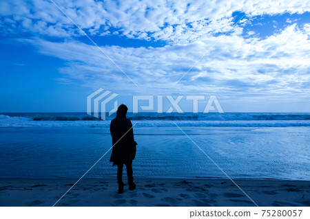 一個人看著大海在閃亮的海灘的陰影 一個人看著大海在閃亮的海灘的陰影 75280057