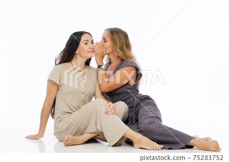 Two beautiful female in casual clothes gossiping on white background. 75283752