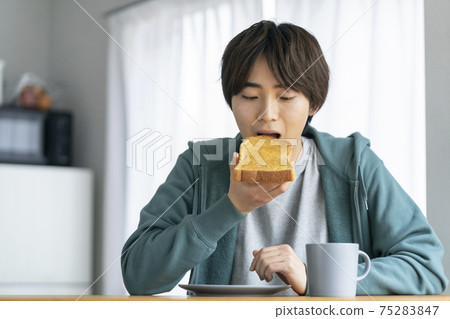 Young man eating toast 75283847