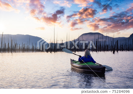 Adventurous Girl kayaking on an infatable kayak in a beautiful lake Adventurous Girl kayaking on an infatable kayak in a beautiful lake 75284096