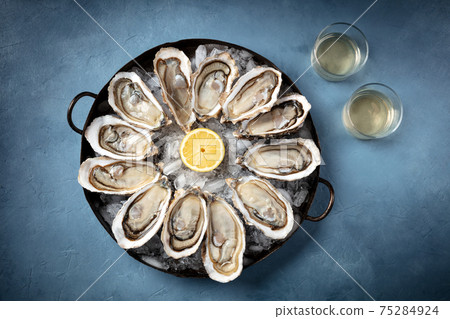 Oysters on ice, lemon, and white wine, overhead flat lay shot Oysters on ice, lemon, and white wine, overhead flat lay shot 75284924