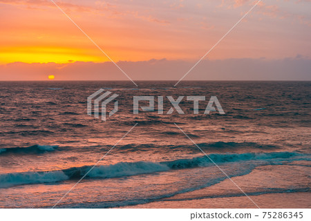 Big yellow sun falling behind the sea 75286345