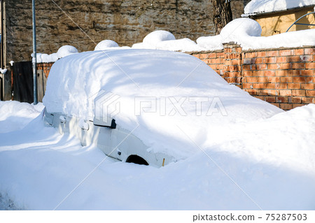 Car under a thick layer of snow after heavy snowfall 75287503