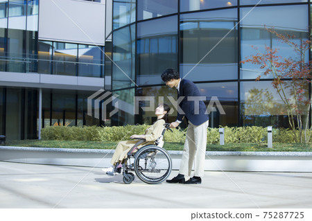 一個坐在輪椅上的女人和一個男人幫助 75287725