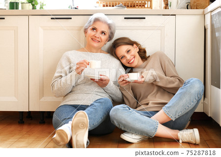Mother and daughter drinking coffee and talking in kitchen 75287818