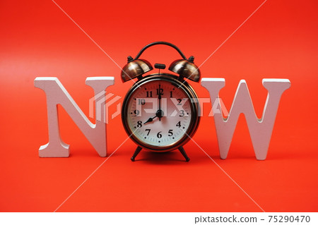 Now alphabet letters with alarm clock on red background Now alphabet letters with alarm clock on red background 75290470