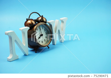 Now alphabet letters with alarm clock on blue background Now alphabet letters with alarm clock on blue background 75290471