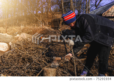 Beautiful young woman chopping firewood with an ax in the village during winter to heat the house. Beautiful young woman chopping firewood with an ax in the village during winter to heat the house. 75291934