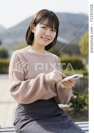 使用智能手機的婦女在公園 使用智能手機的婦女在公園 75293508