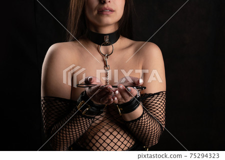 Beautiful woman in the role of a slave on a leash on black background 75294323