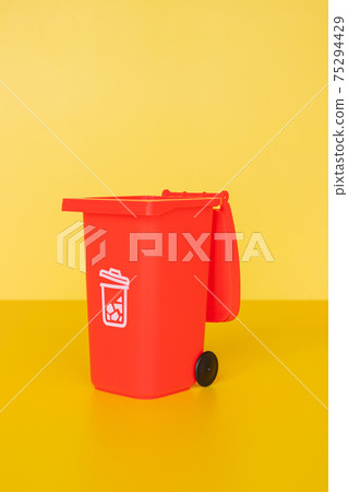 Red garbage container on yellow background Red garbage container on yellow background 75294429