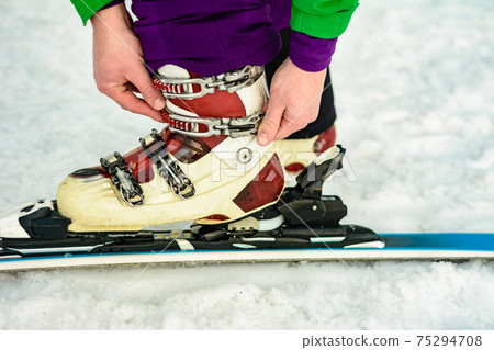 The skier wears footwear for skiing and fixes the fastener The skier wears footwear for skiing and fixes the fastener 75294708