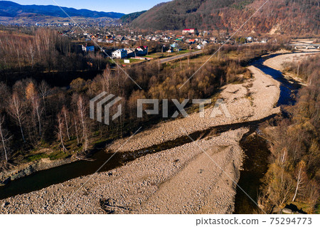 Carpathian village in Ukraine, autumn view of the village, river and mountains from a bird's eye view, aerial photography of the Carpathian region. Carpathian village in Ukraine, autumn view of the village, river and mountains from a bird's eye view, aerial photography of the Carpathian region. 75294773