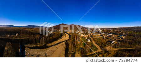 Carpathian village in Ukraine, autumn view of the village, river and mountains from a bird's eye view, aerial photography of the Carpathian region. 75294774