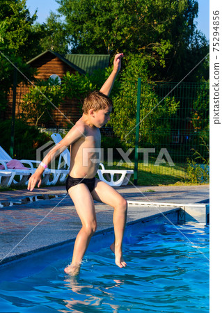 The boy jumps into the pool, children's games and entertainment in the aqua park. The boy jumps into the pool, children's games and entertainment in the aqua park. 75294856