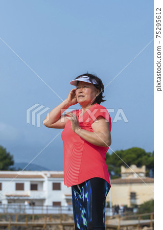 Asian woman with running gear fixing her hair Asian woman with running gear fixing her hair 75295612