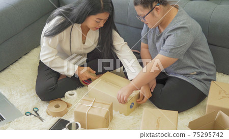 Asian woman and daughter, a family, packing postal parcel packaging carton box delivery, working from home, selling products online business. Shipping service. People lifestyle in coronavirus pandemic Asian woman and daughter, a family, packing postal parcel packaging carton box delivery, working from home, selling products online business. Shipping service. People lifestyle in coronavirus pandemic 75295742